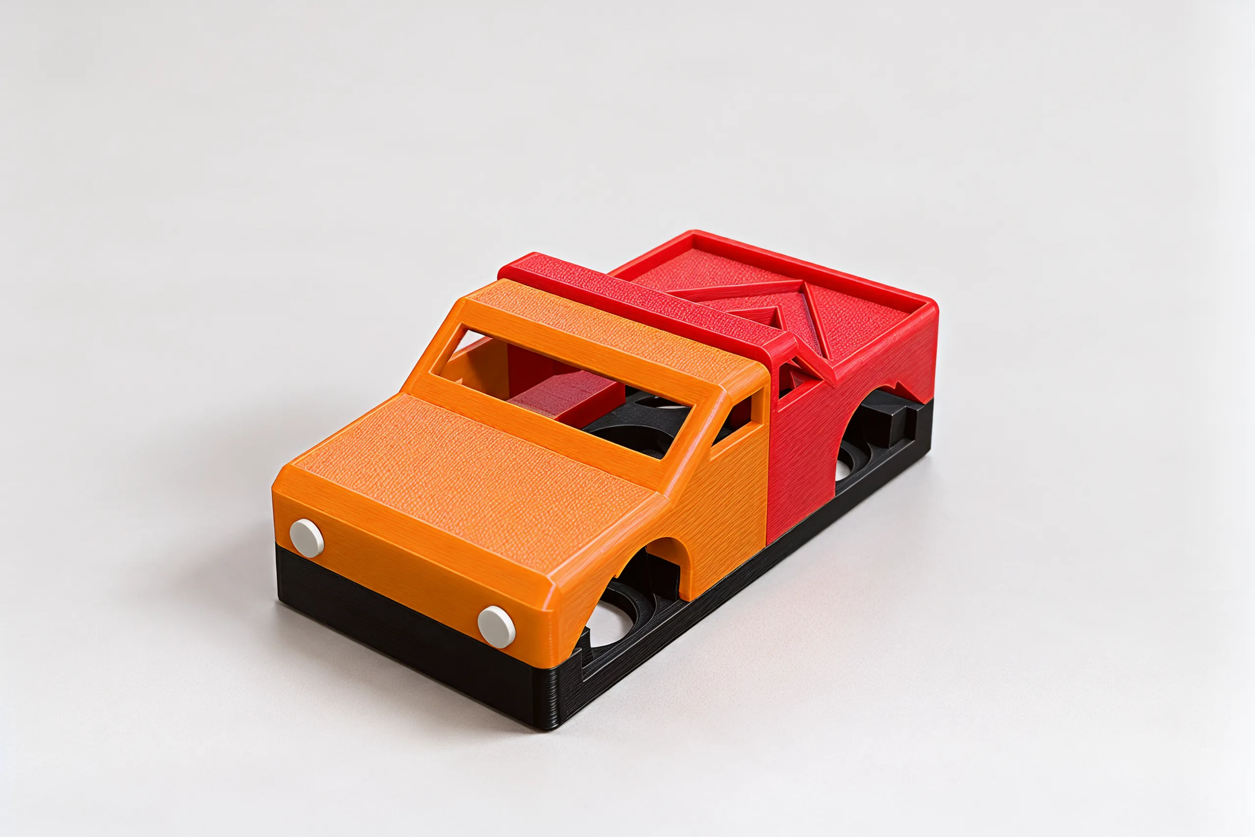 Studio photo of a sports-coupe front in orange on a red pickup back, sitting on a black chassis