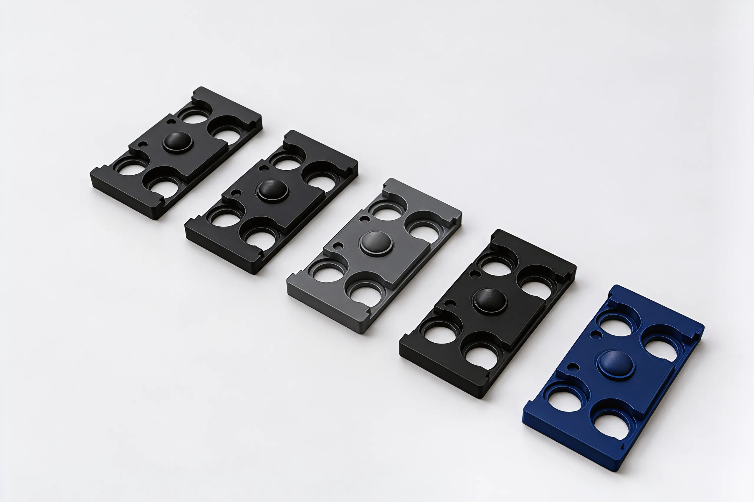 Five bare chassis in a diagonal row, four black or grey and one navy, each with four round holes and a raised dome in the middle