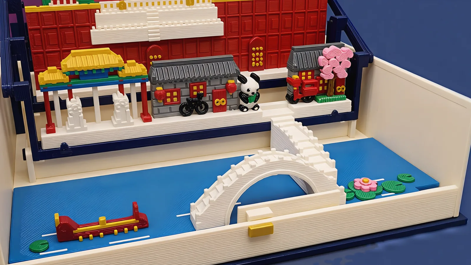 The front of the open book: a blue water plate in the cream tray with a red dragon boat with gold details, lily pads and a pink lotus, and a white stone bridge with one round arch whose stair climbs to the street; on the street behind it a painted archway on red posts over two pale stone lions, a grey-brick house with red lanterns and a black bicycle, a black-and-white panda at the top of the stair, a second house with a red rickshaw and a tree in pink blossom, and the red palace wall with its white terrace behind