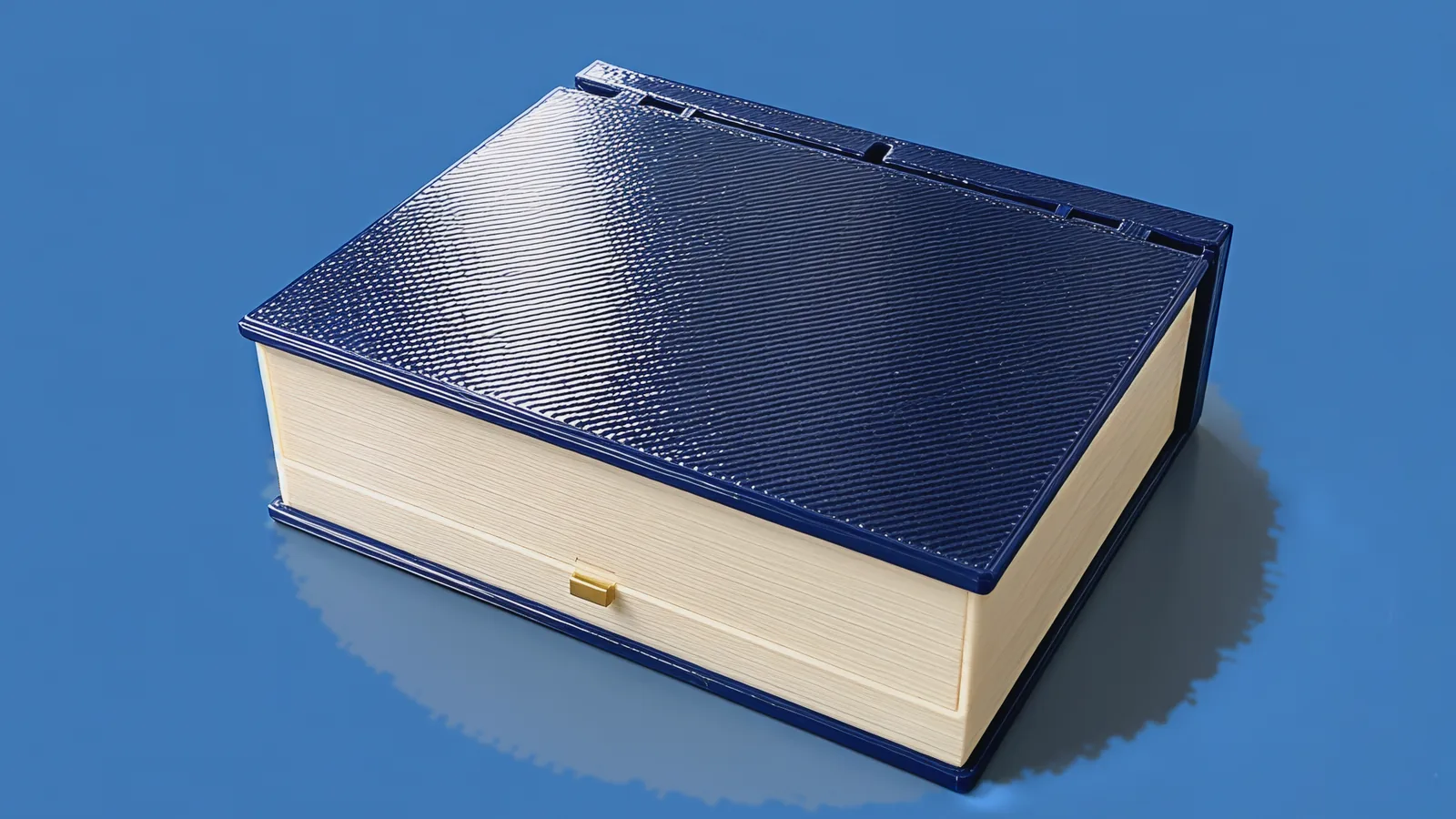 The closed Moonlit Atlas book: navy cover, cream page block and a brass button