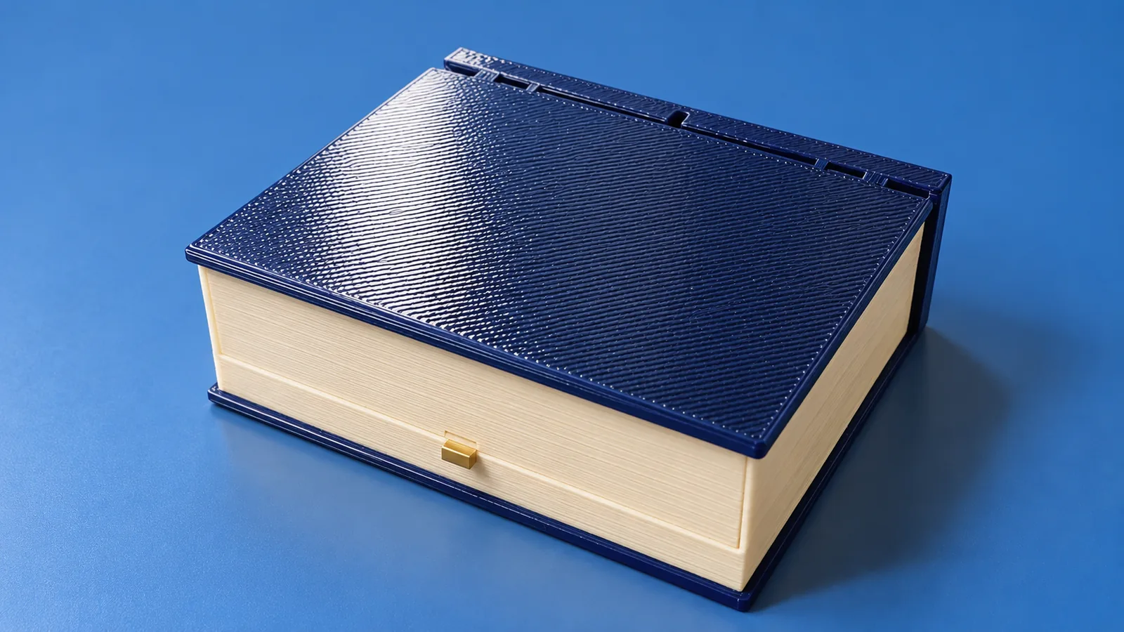 The closed Moonlit Atlas book: navy cover, cream page block and a brass button