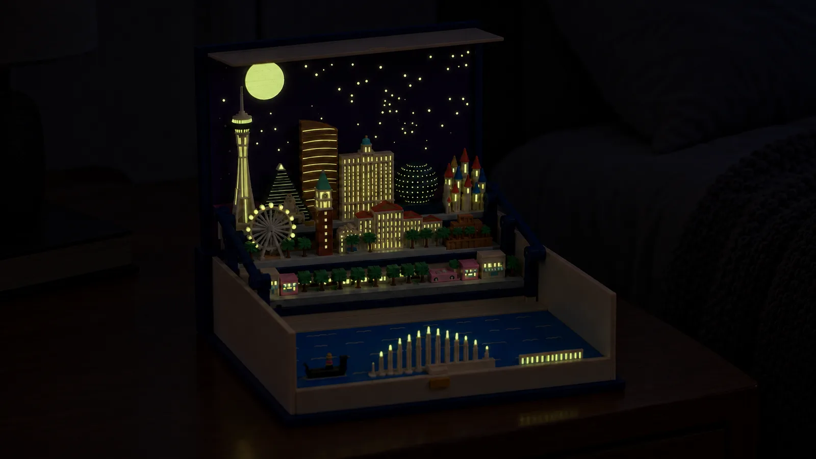 The open book with the Las Vegas pack on a bedside table in a dark bedroom, its moon, stars and windows glowing