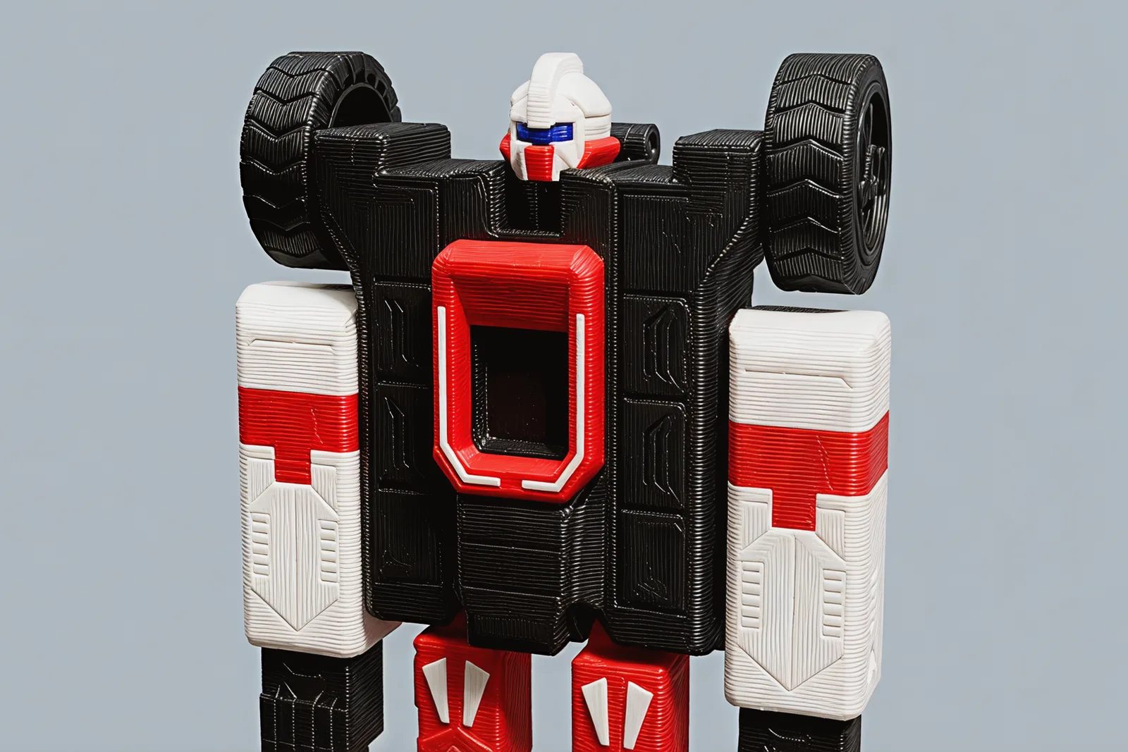 Close on the chest: the white helmet with its blue visor between two shoulder wheels, and the red halo around the cockpit opening.