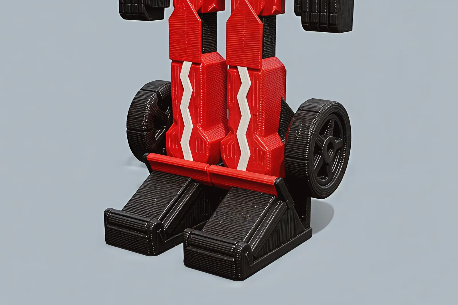 Close on the feet: two black wedge boots, each carrying a folded red-bladed wing half on its toe, with a rear wheel beside each shin.