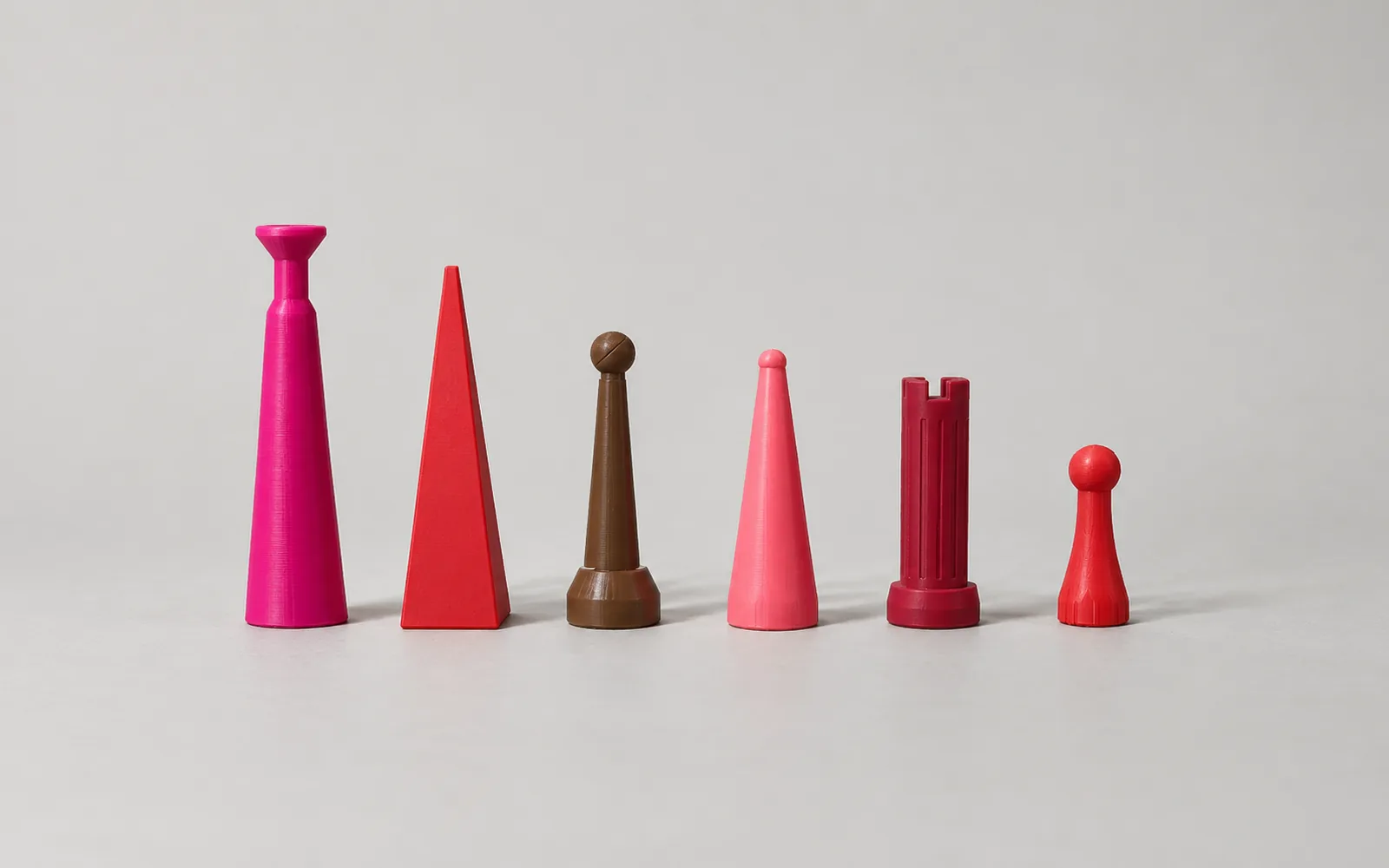 The six warm-side shapes in a row from tallest to shortest: magenta king, red queen, brown bishop, pink knight, crimson rook, red pawn